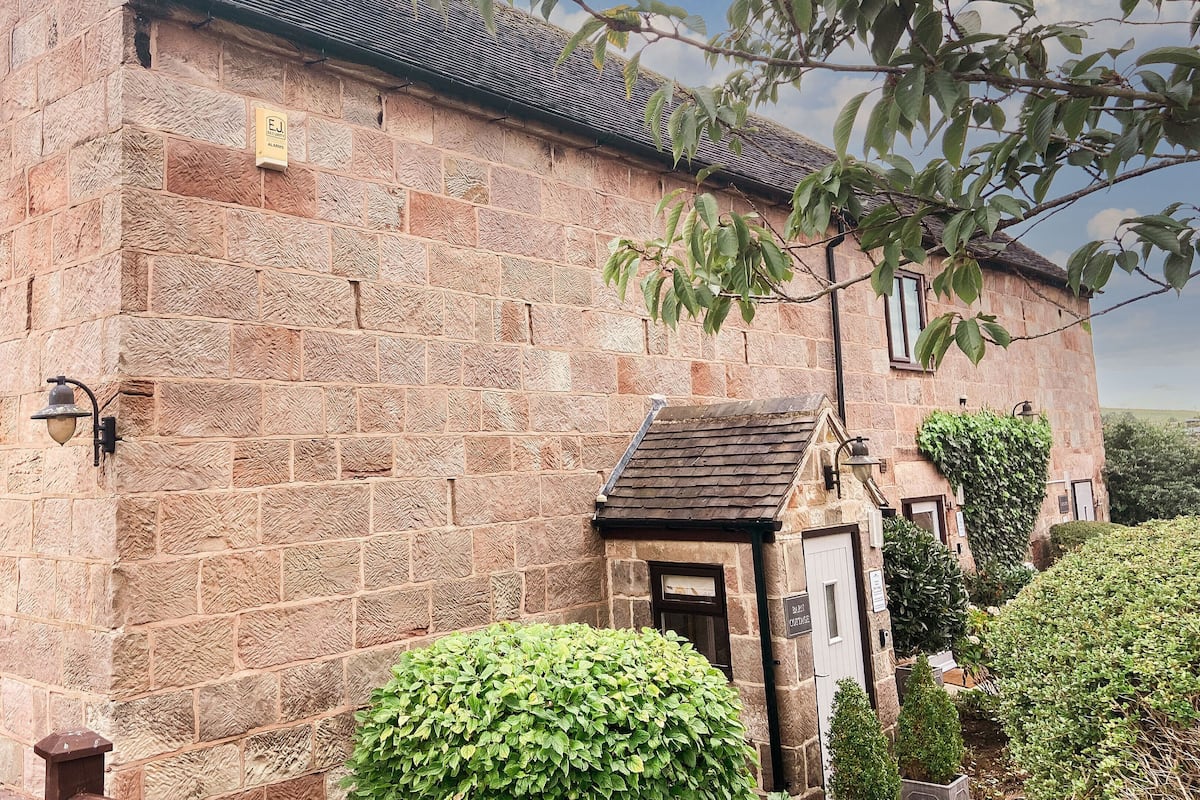 A stone building with a small entrance, a window, and a sign indicating it is a guesthouse.
