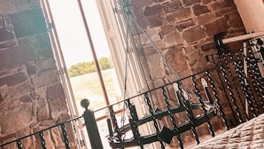 A room with stone walls, a bed with a white bedspread, and a window with a view of greenery outside. - Horsley Lodge Hotel (Derby)