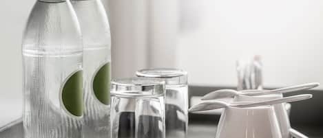 A tray with a bottle, two glasses, a salt shaker, and a pitcher.