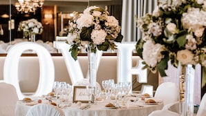A wedding reception table with floral centerpieces, a large 'LOVE' sign, and neatly arranged glassware and plates. - Horsley Lodge Hotel (Derby)