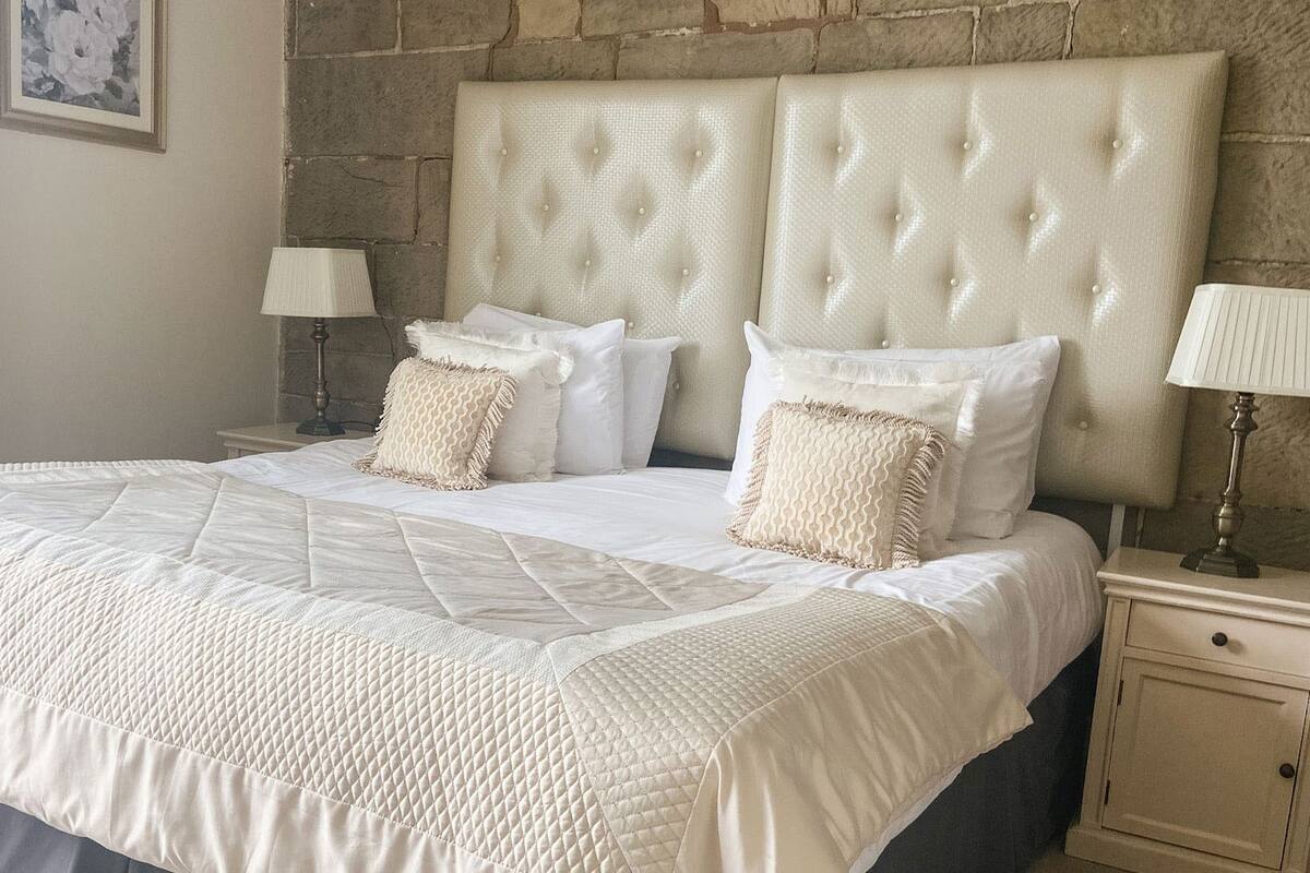 A neatly made bed with a quilted duvet, two bedside tables with lamps, and a headboard with a tufted design.