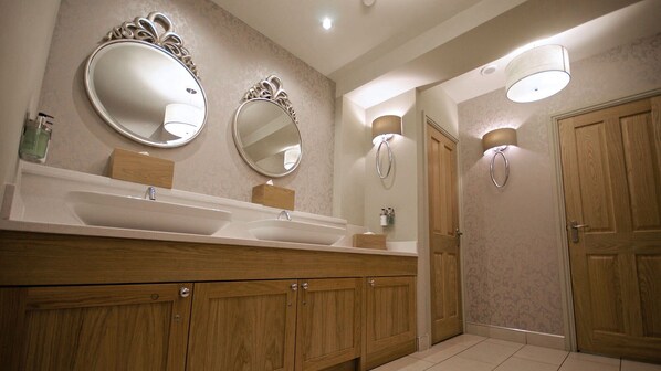 A modern bathroom with two sinks, wooden cabinets, and wall-mounted mirrors.
