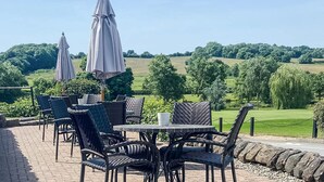 An outdoor patio with wicker furniture and umbrellas, overlooking a green landscape. - Horsley Lodge Hotel (Derby)