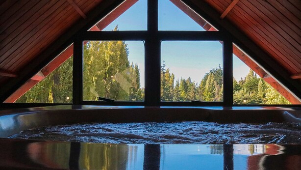 Ein Whirlpool in einem Raum mit schrägverdeckter Decke und großen Fenstern.