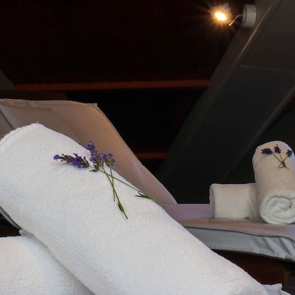 A spa chair with a rolled towel and a small bouquet of lavender.