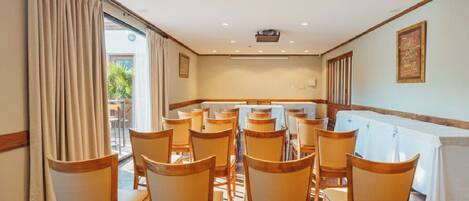 A conference room with wooden chairs and a white tablecloth.