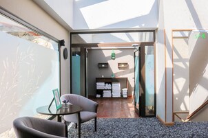 A hotel lobby with a seating area, a reception desk, and a view of the street.