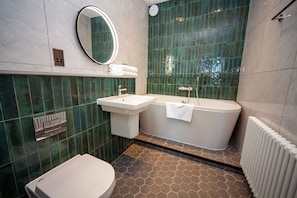 Et badeværelse med toilet, vask og badekar.