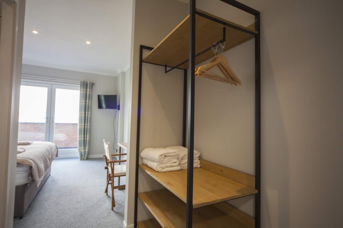 A bedroom with a bunk bed, a desk, and a TV mounted on the wall.