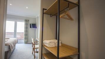 A bedroom with a bunk bed, a desk, and a TV mounted on the wall.
