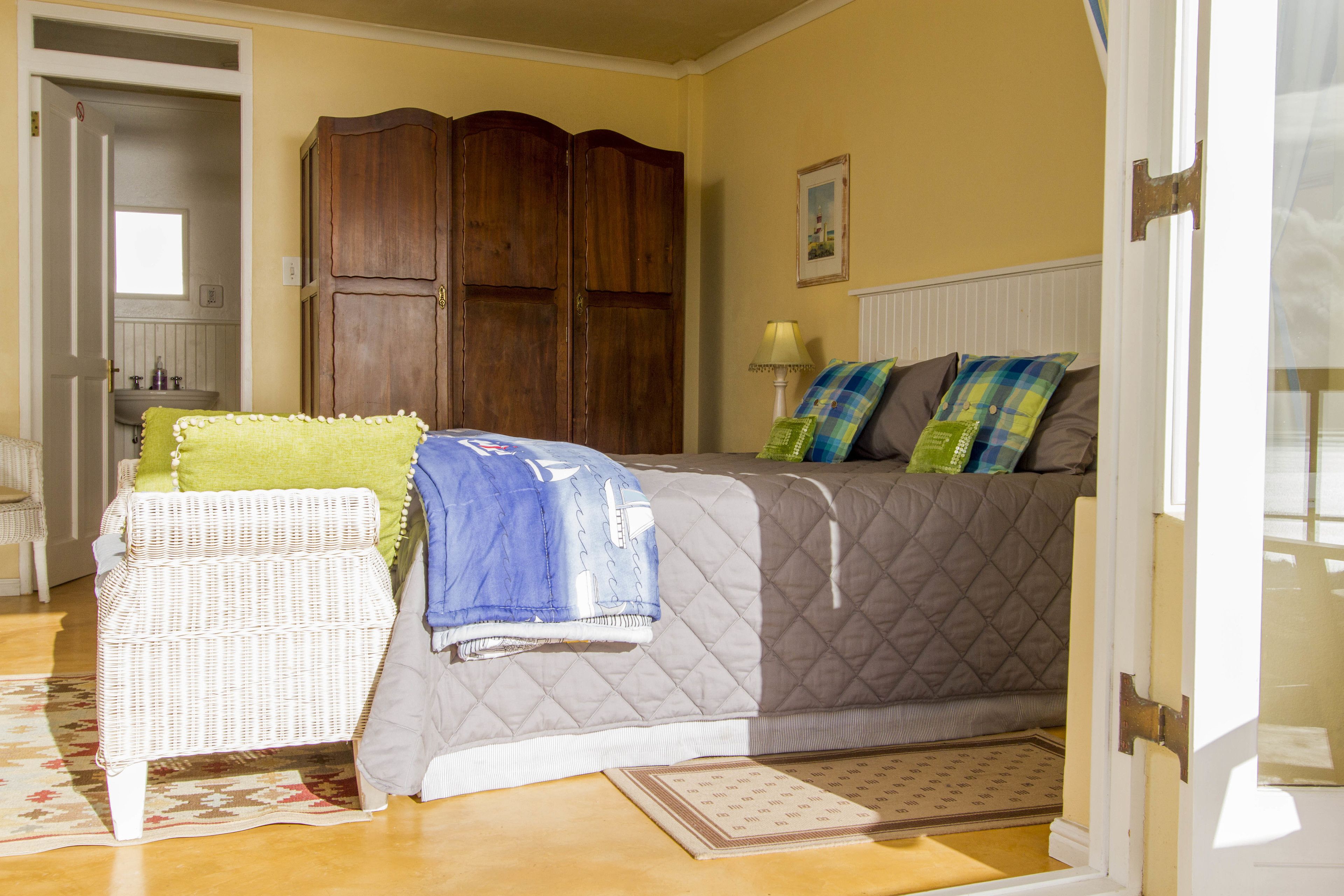 A bedroom with a bed, a chair, a wardrobe, and a door.