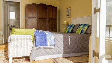 A bedroom with a bed, a chair, a wardrobe, and a door.