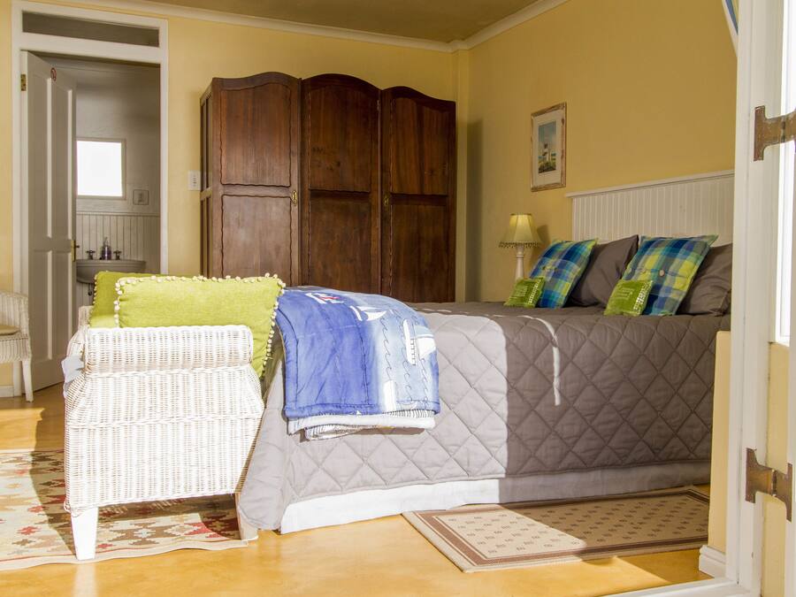 A bedroom with a bed, a chair, a wardrobe, and a door.