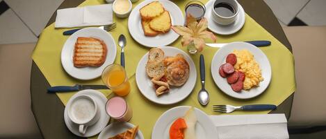 Un desayuno con diversos platos, como tostadas, huevos revueltos y una rebanada de fruta.