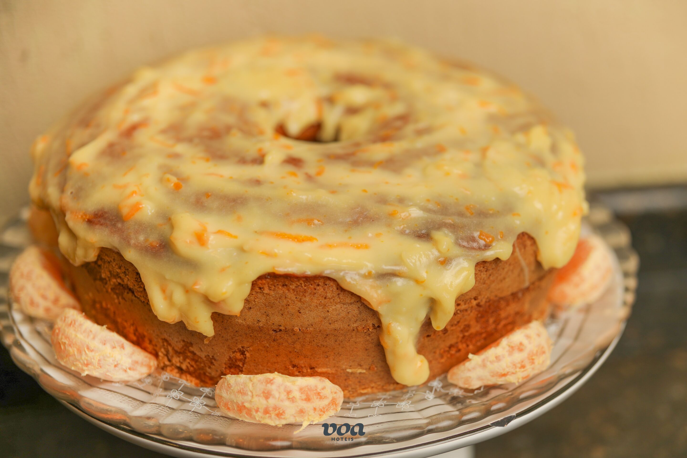 Un bizcocho Bundt con cobertura cremosa sobre un plato de vidrio.