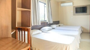 Habitación de hotel con dos camas, un televisor montado en la pared y una ventana con cortinas.