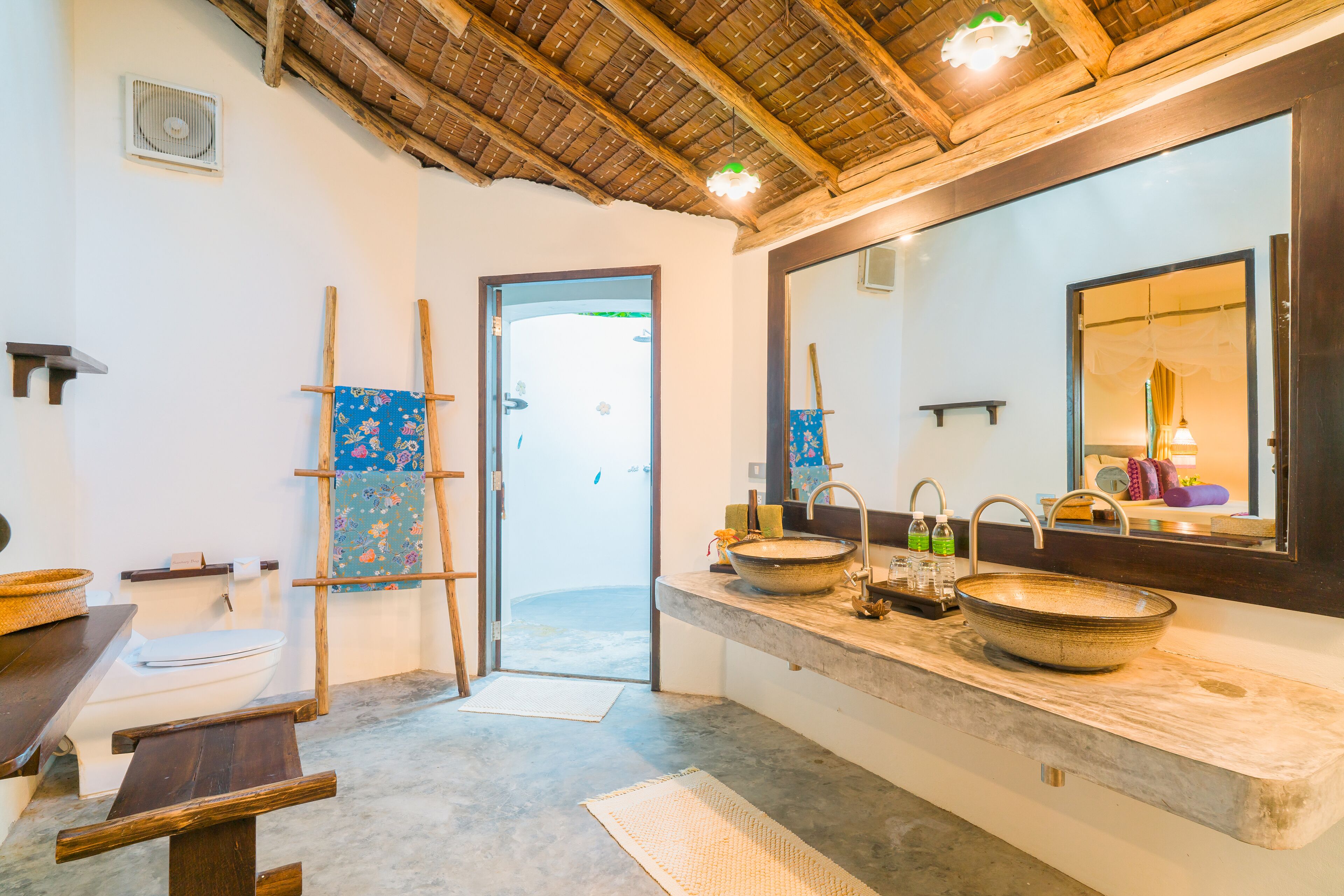 A bathroom with a large mirror, wooden ceiling, and a rustic aesthetic.