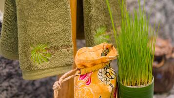 Un plateau en bois avec une serviette, un récipient décoratif, une plante en pot, une fleur et une noix de coco.