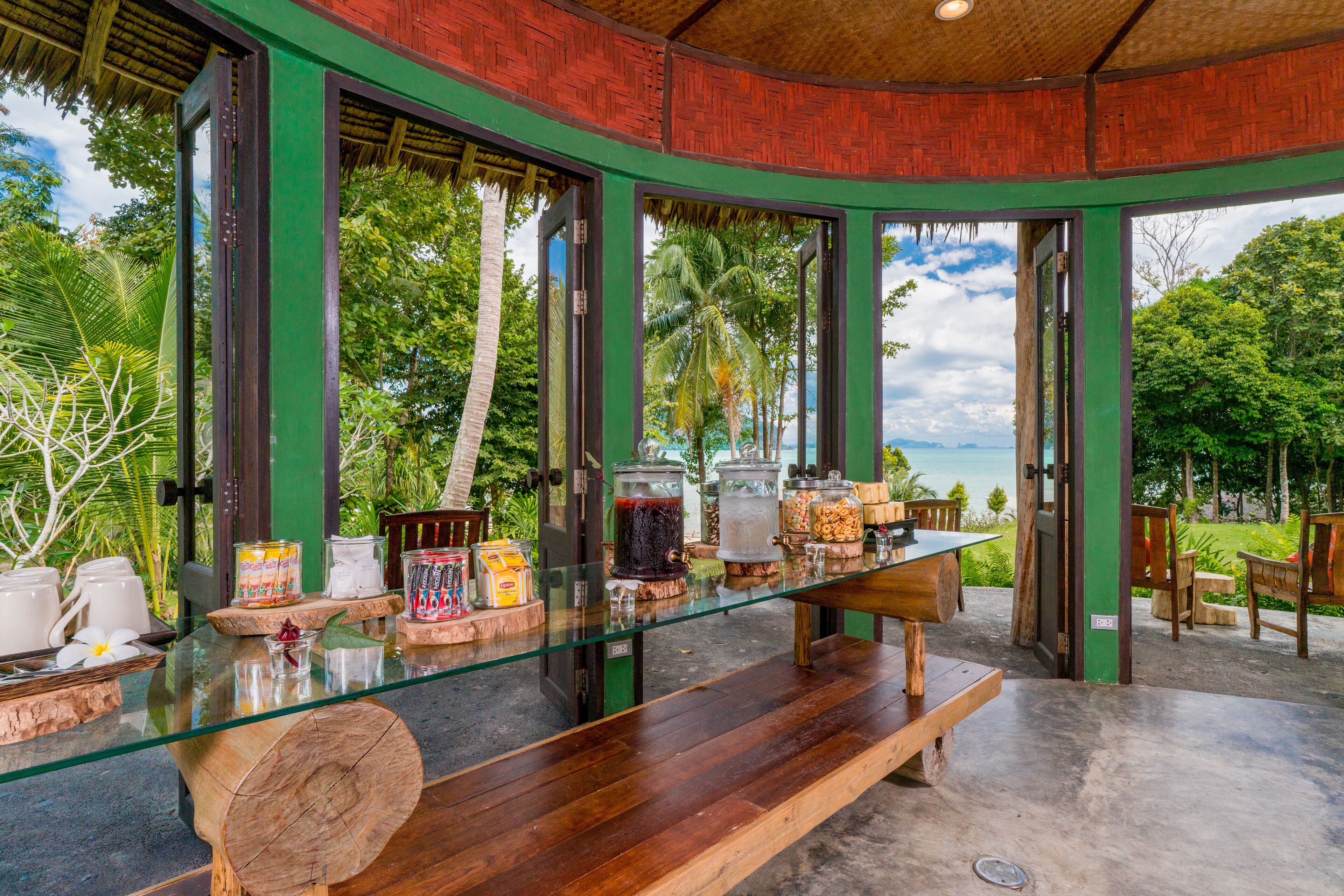 A tropical resort bar with a glass counter, wooden stools, and a view of the ocean.