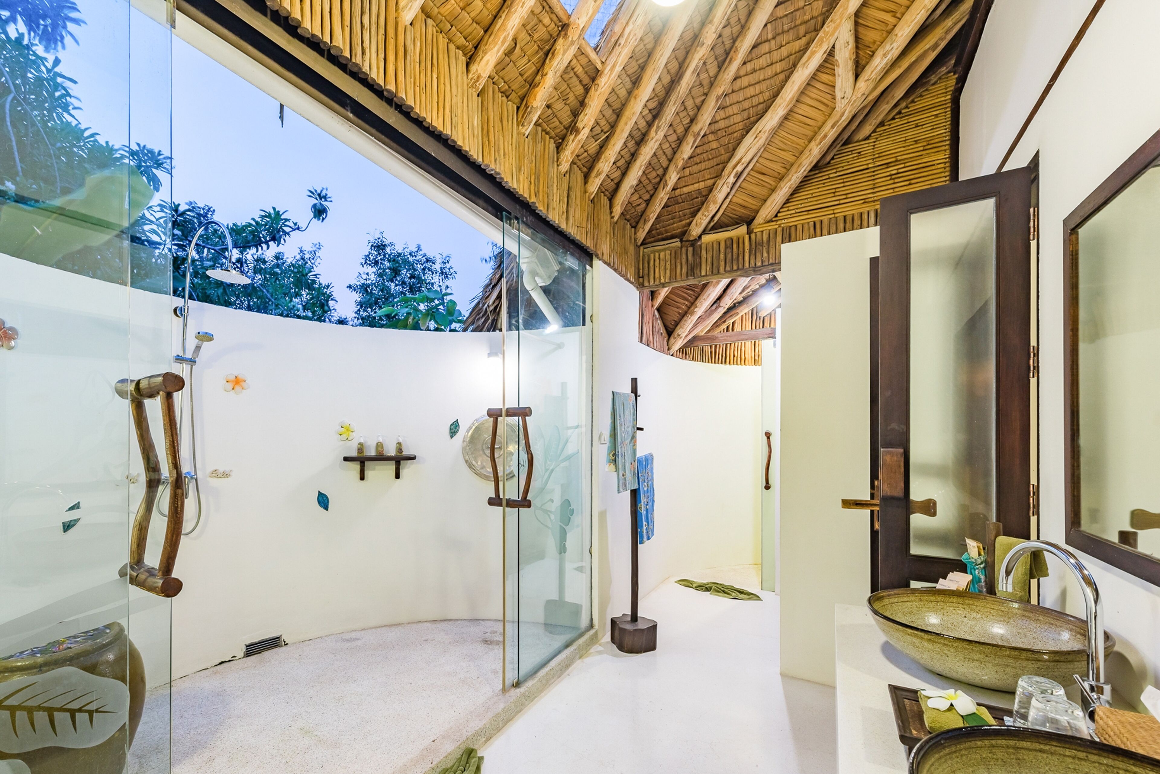 A modern bathroom with a glass shower enclosure, a wooden ceiling, and a large mirror.