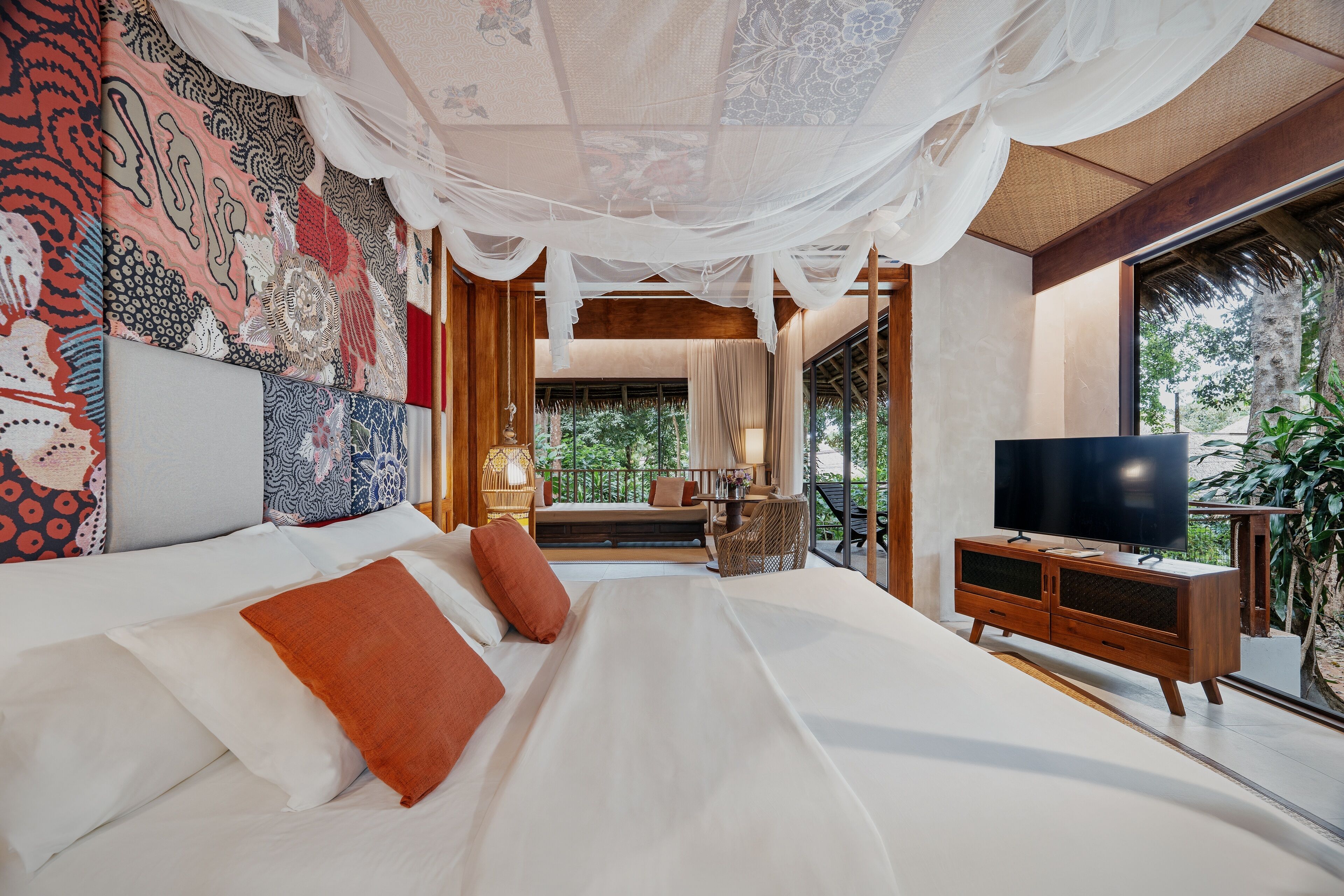 A bedroom with a large bed, a television, and a view of the outdoors.