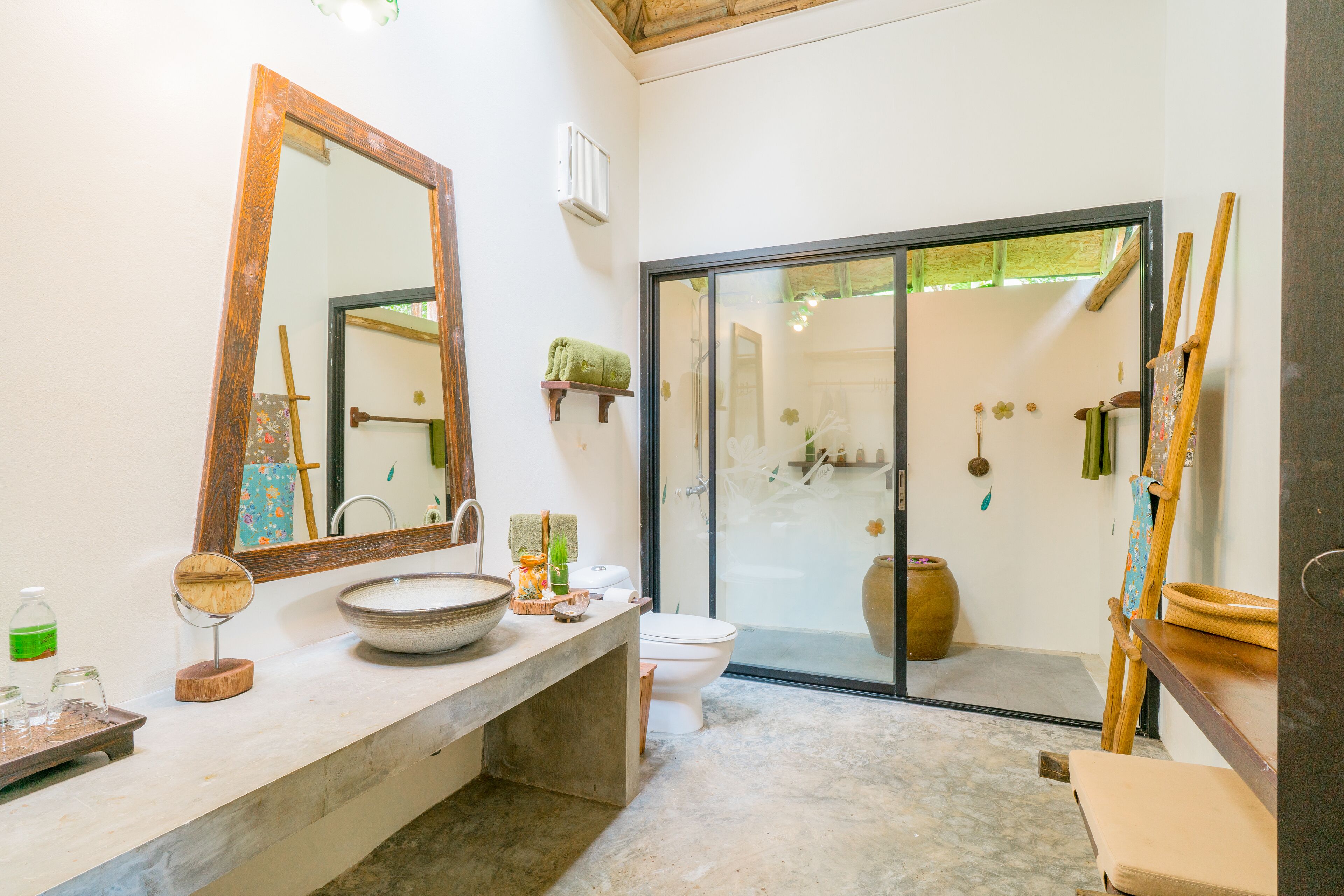 A bathroom with a large mirror, a sink, a toilet, and a shower area.
