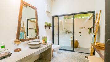A bathroom with a large mirror, a sink, a toilet, and a shower area.