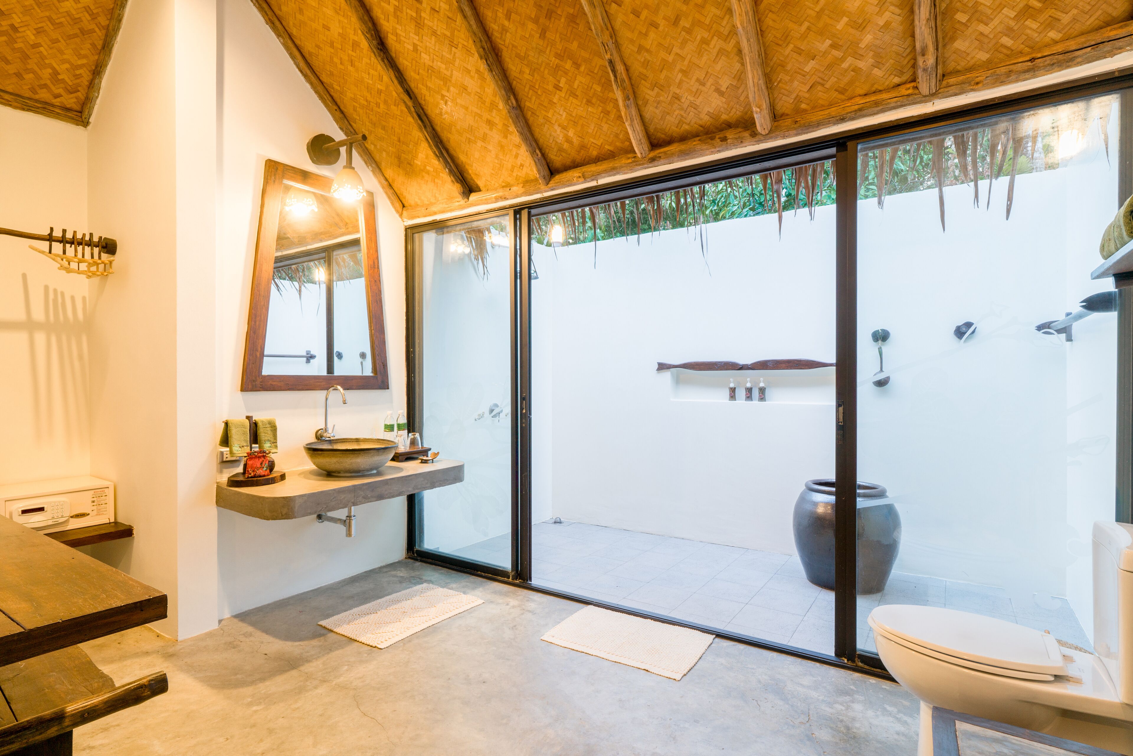 A modern bathroom with a large mirror, a sink, a toilet, and a shower area visible through glass doors.