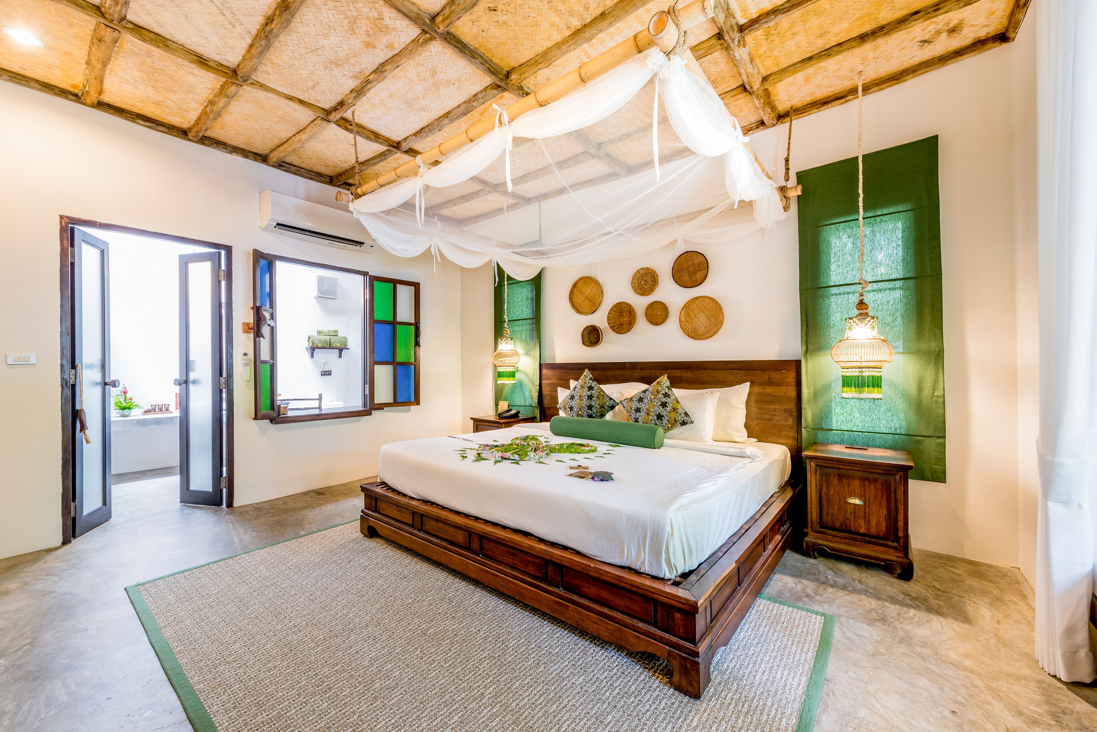A spacious bedroom with a large bed, a wooden headboard, and a green accent wall.