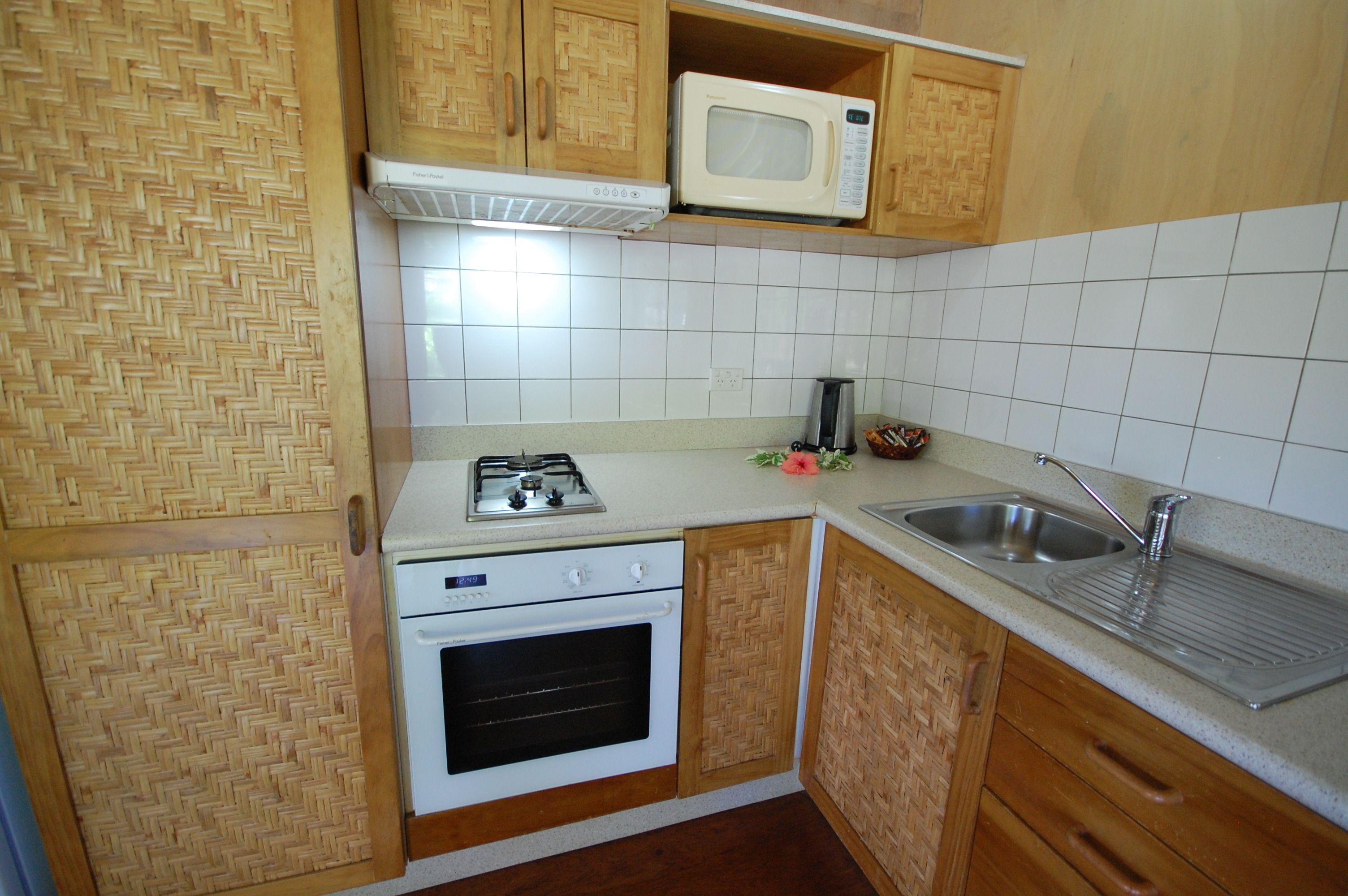 Een kleine keuken met een gasfornuis, oven, magnetron en een spoelbak.