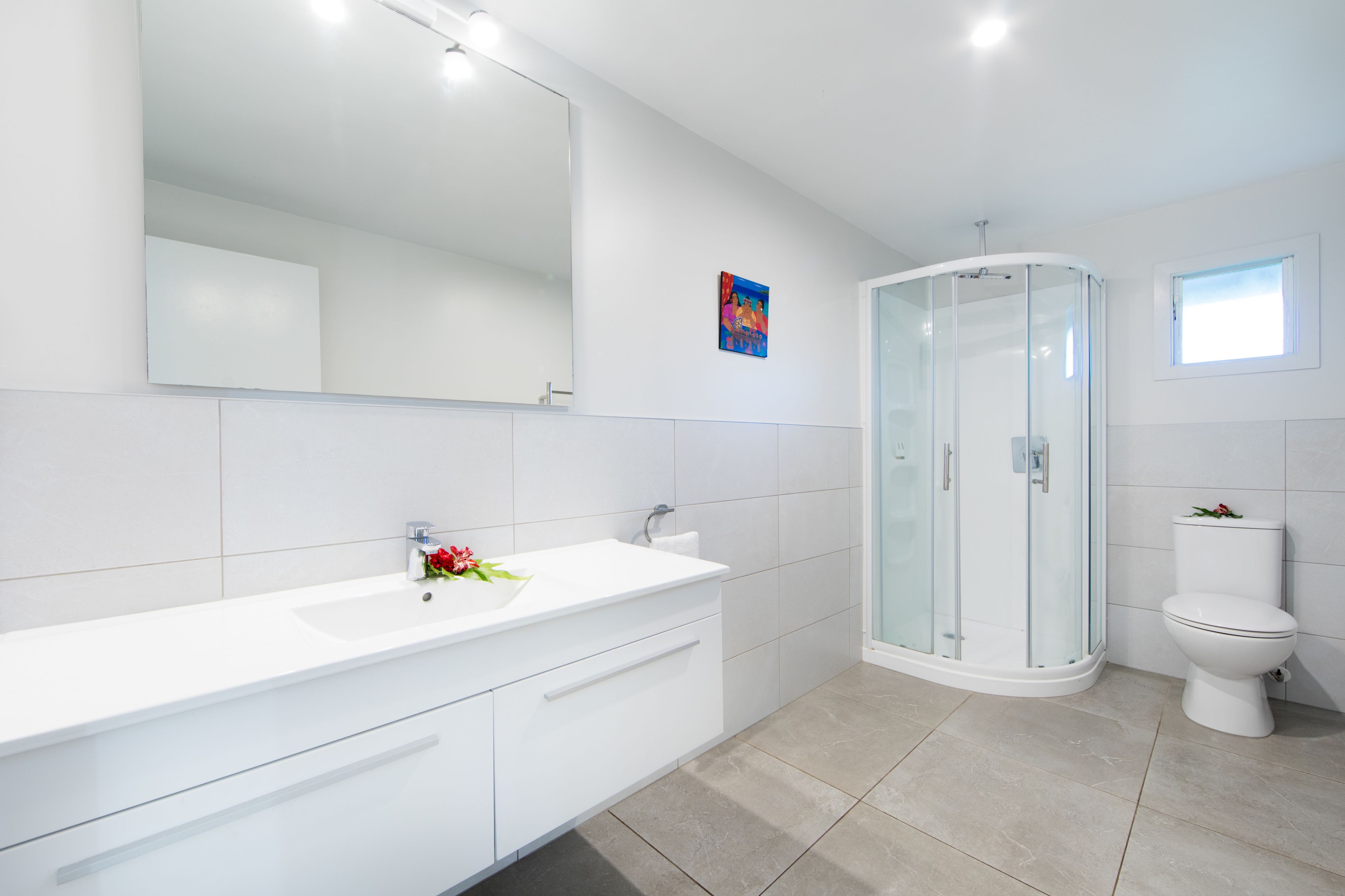 A modern bathroom with a white vanity, a glass shower enclosure, and a toilet.
