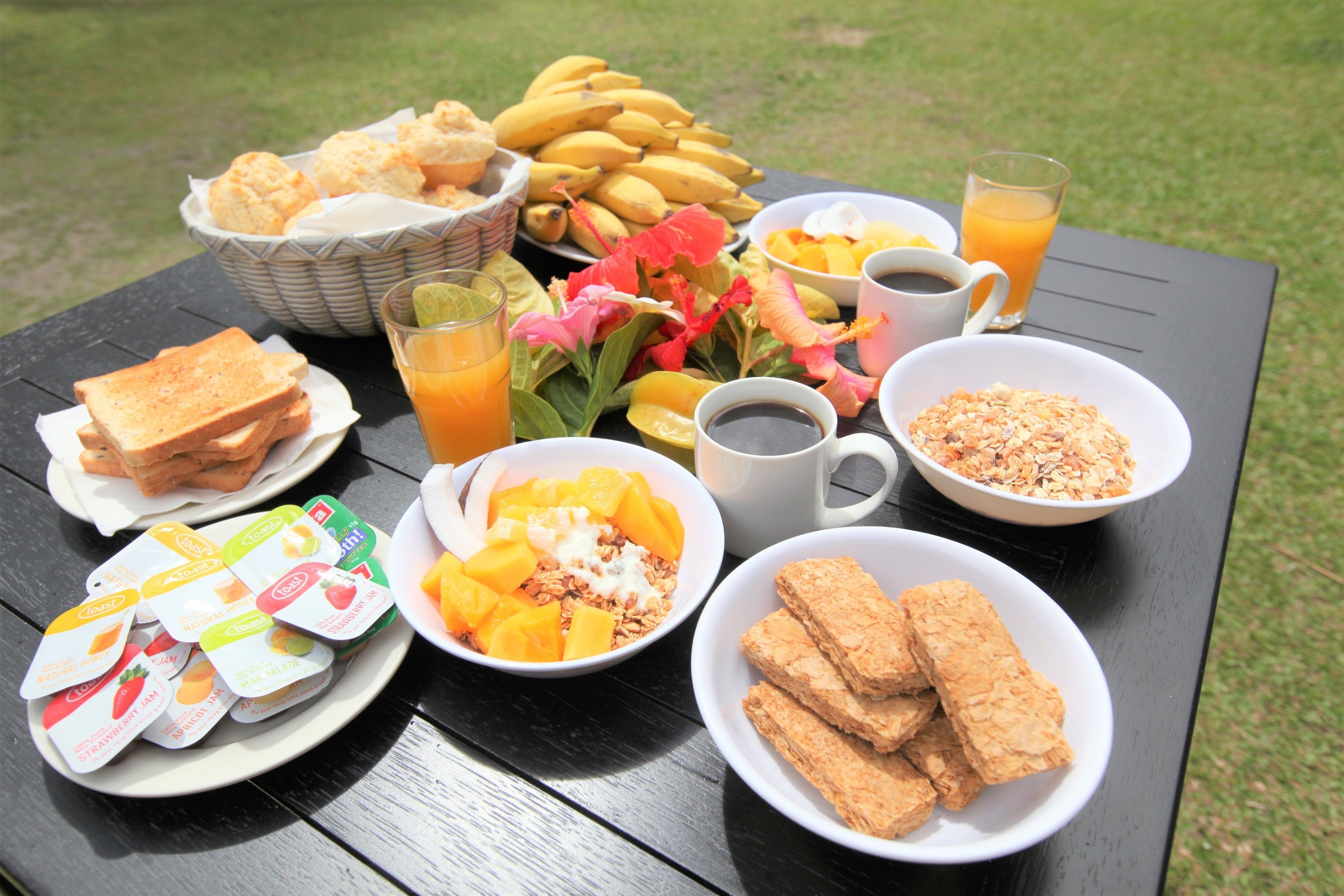 A picnic table with various food items including sandwiches, fruit, and beverages.