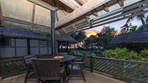 An outdoor deck with wooden furniture and a thatched roof structure. - Lagoon Breeze Villas (Rarotonga)