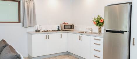 A modern kitchen with white cabinets, a stainless steel refrigerator, a microwave, and a sink.