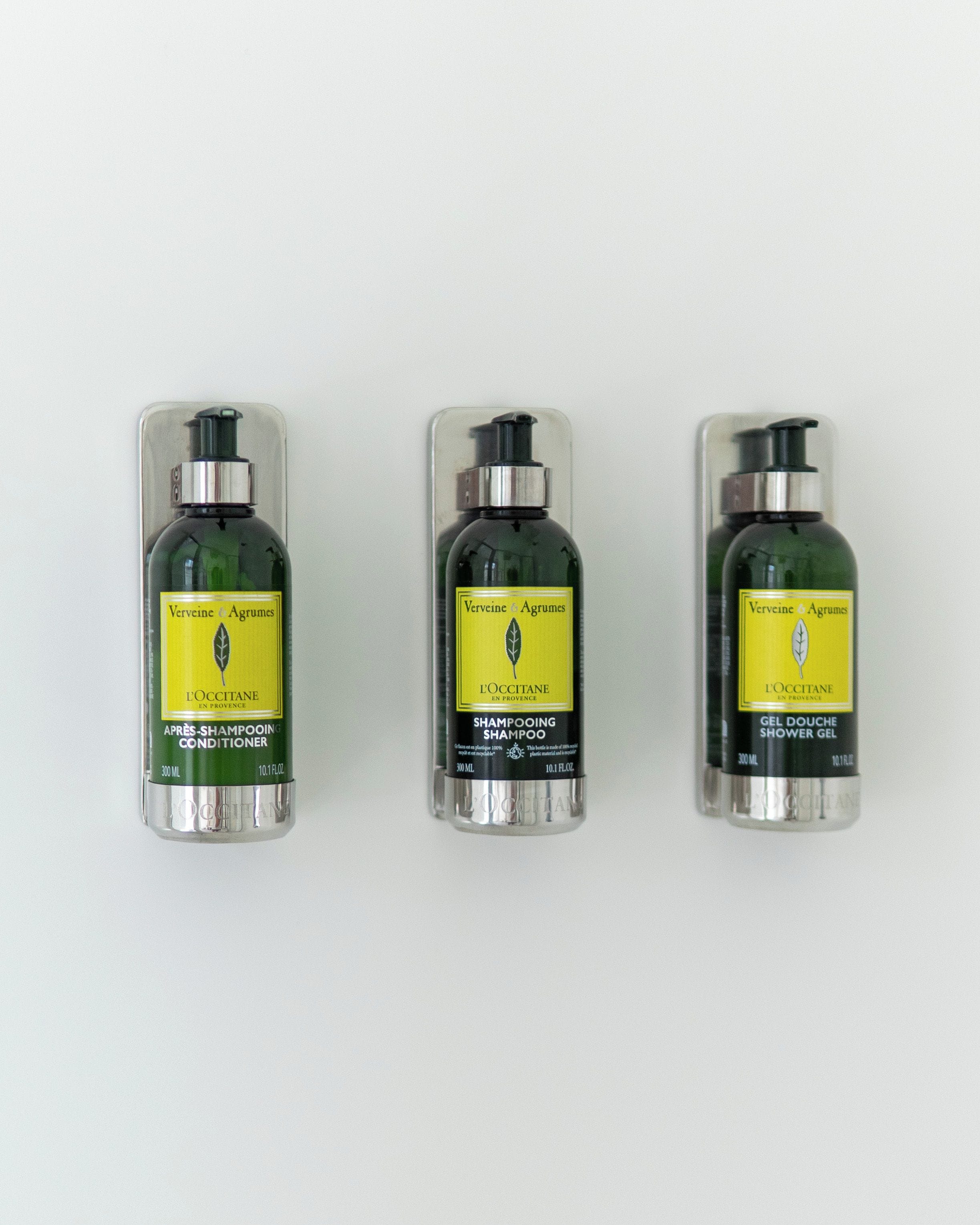 Three bottles of L'OCCITANE shampoo and conditioner.