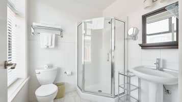 Een moderne badkamer met een glazen douchecabine, een wit wastafelmeubel en een toilet.