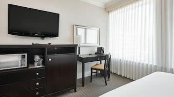 A hotel room with a bed, a desk with a chair, a television, a coffee maker, and a microwave.