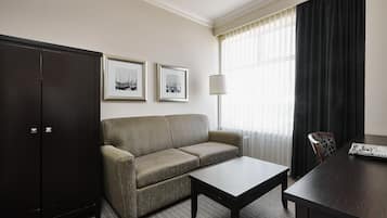 A hotel room with a sofa, a table, a cabinet, and two framed pictures on the wall.