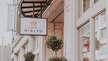 A hotel sign for RIALTO with a classic architectural facade and a covered entrance.