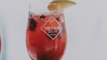 Een cocktailglas met een logo en tekst, dat aangeeft dat het van The Palms bij Hotel Rialto is, geïnspireerd op details uit de keuken en cocktails.