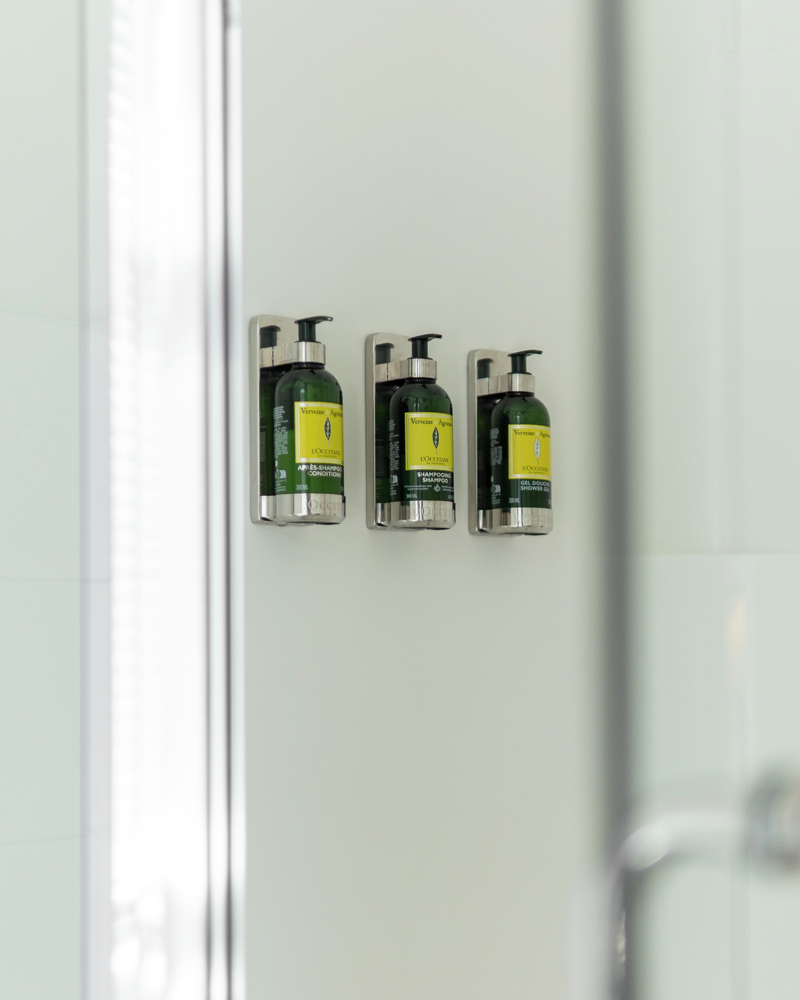 Three bottles of Vervine & Agris shower gel on a bathroom wall.