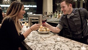 A marble bar with a bowl of fruit and a wine glass.