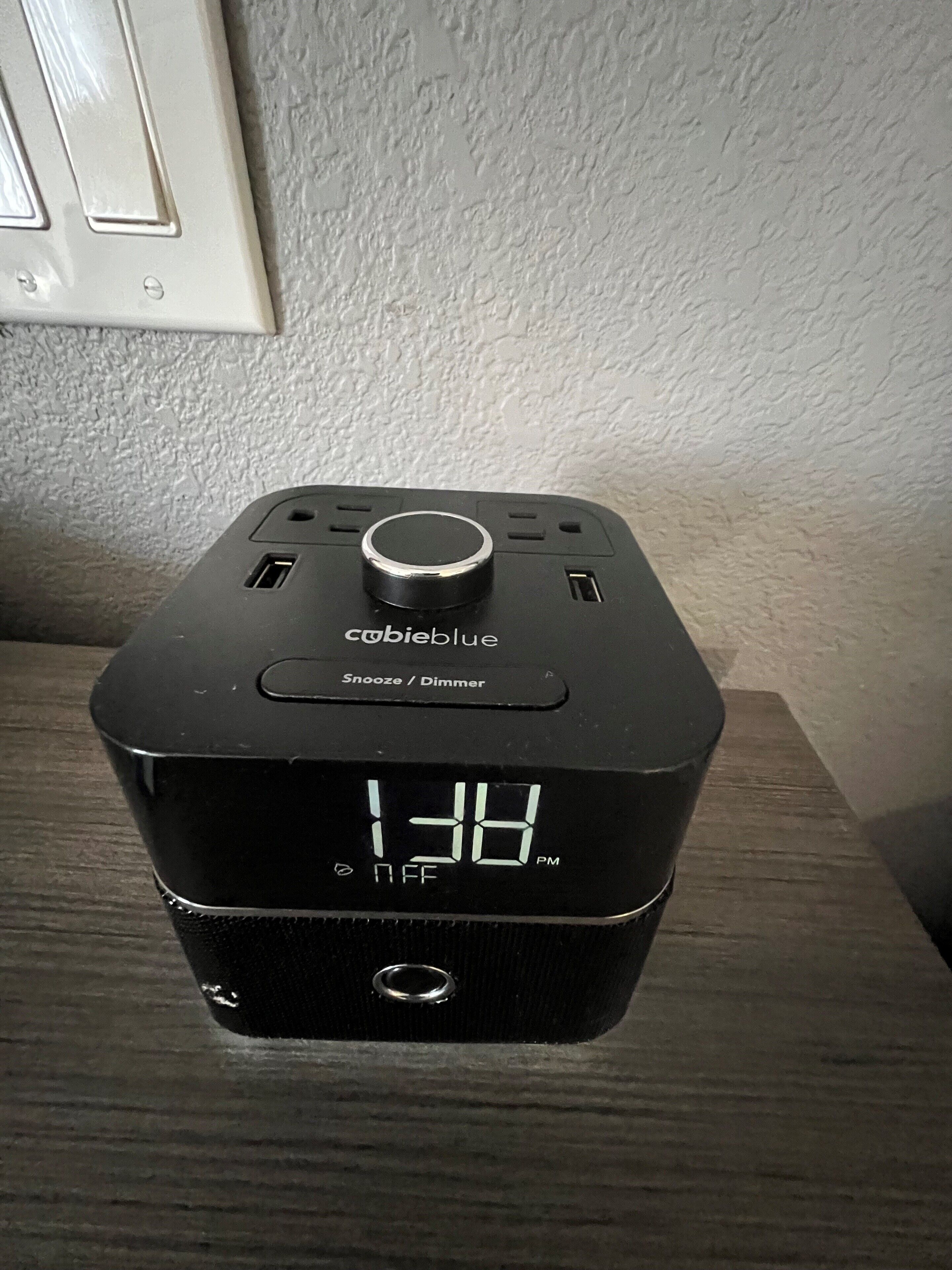 A black digital clock with the brand 'Cohibieblue' on a wooden surface.