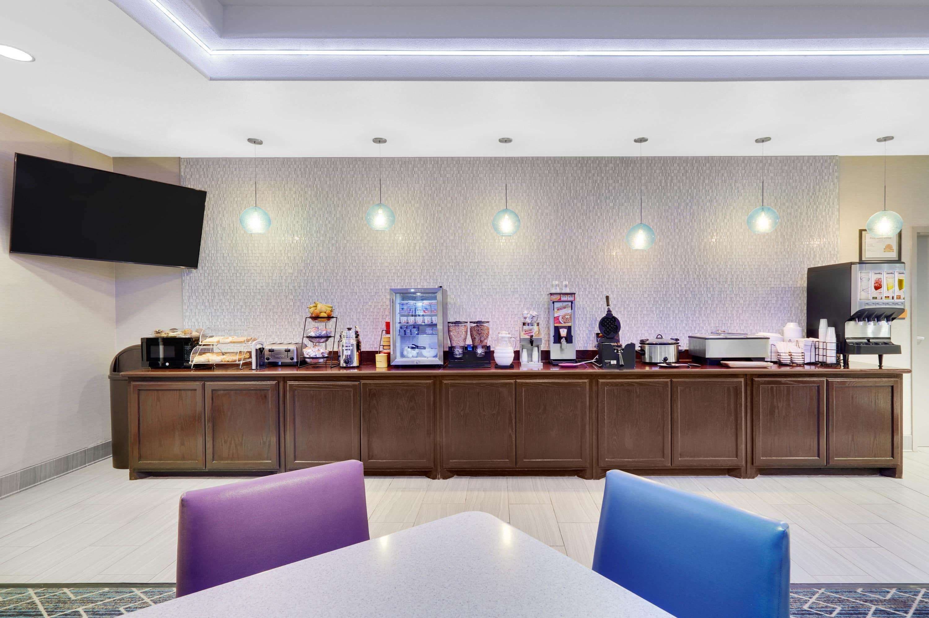 Zona de recepción de hotel con mostrador, asientos y televisor de pared.