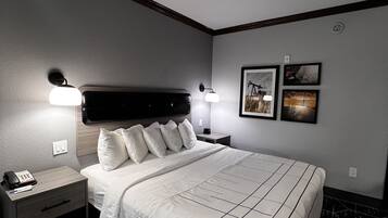 A hotel room with a large bed, bedside tables, a phone, and artwork on the wall.