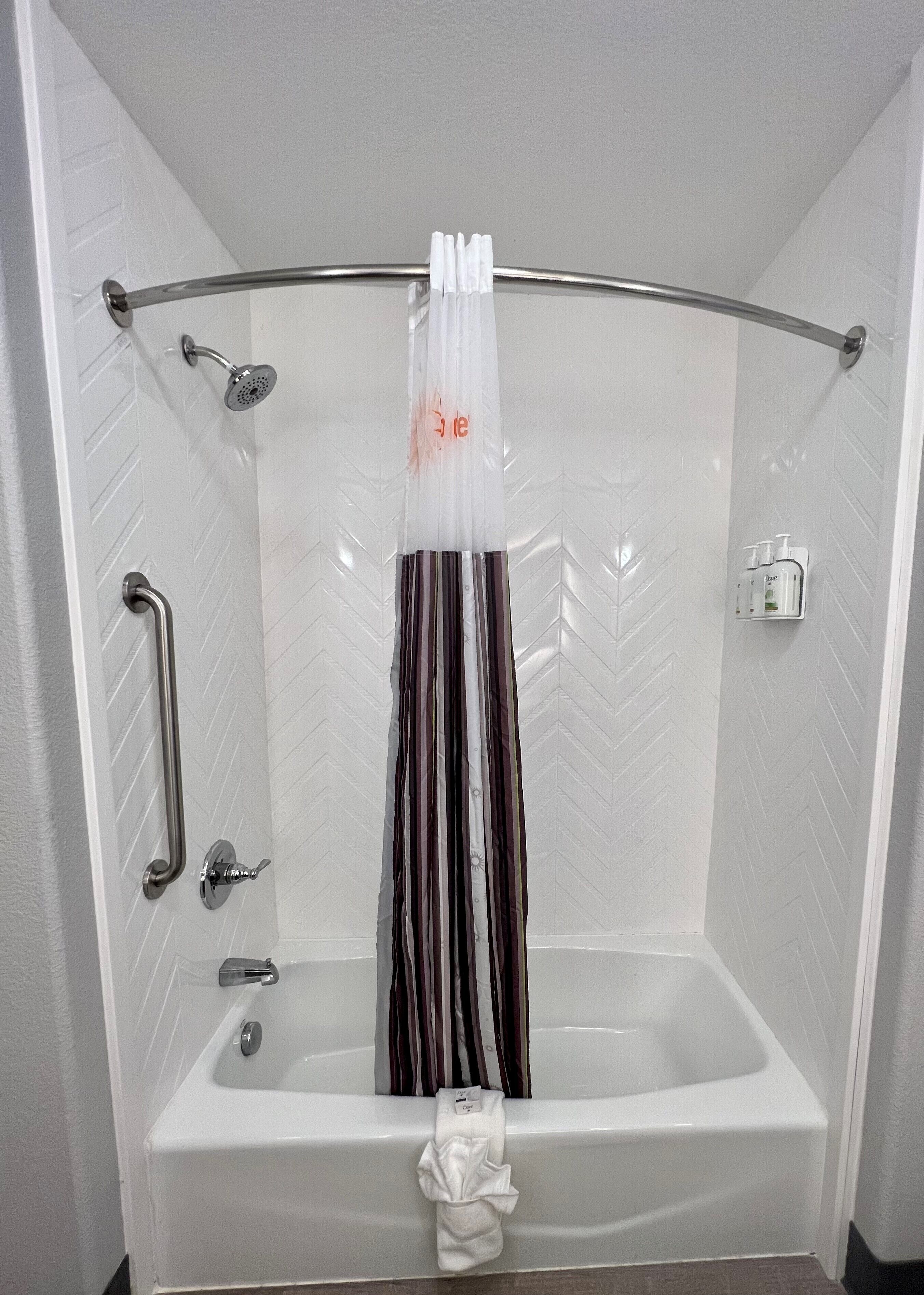 Un baño moderno con ducha, baranda, toallero y una botella de champú.