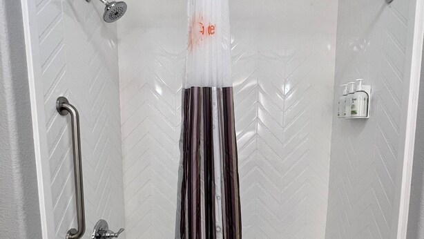 Ein modernes Badezimmer mit Dusche, Handlauf, Handtuchhalter und einer Shampooflasche.