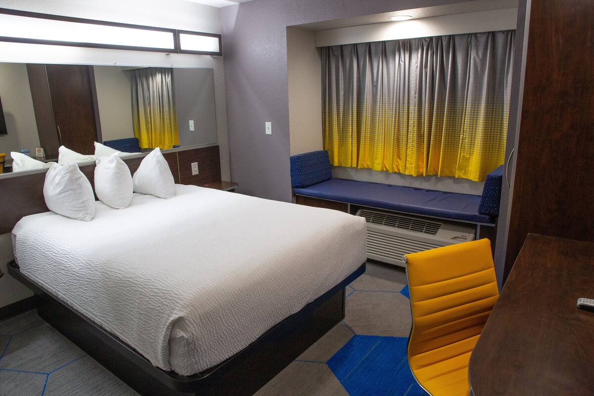 A hotel room with a large bed, a seating area with a view, and a small table.