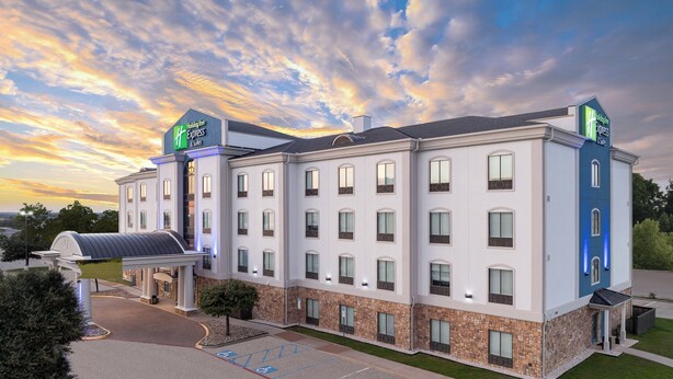 A Holiday Inn Express hotel with a modern design, featuring a large parking lot and a covered entrance. - Holiday Inn Express & Suites Denton North by IHG (Denton)