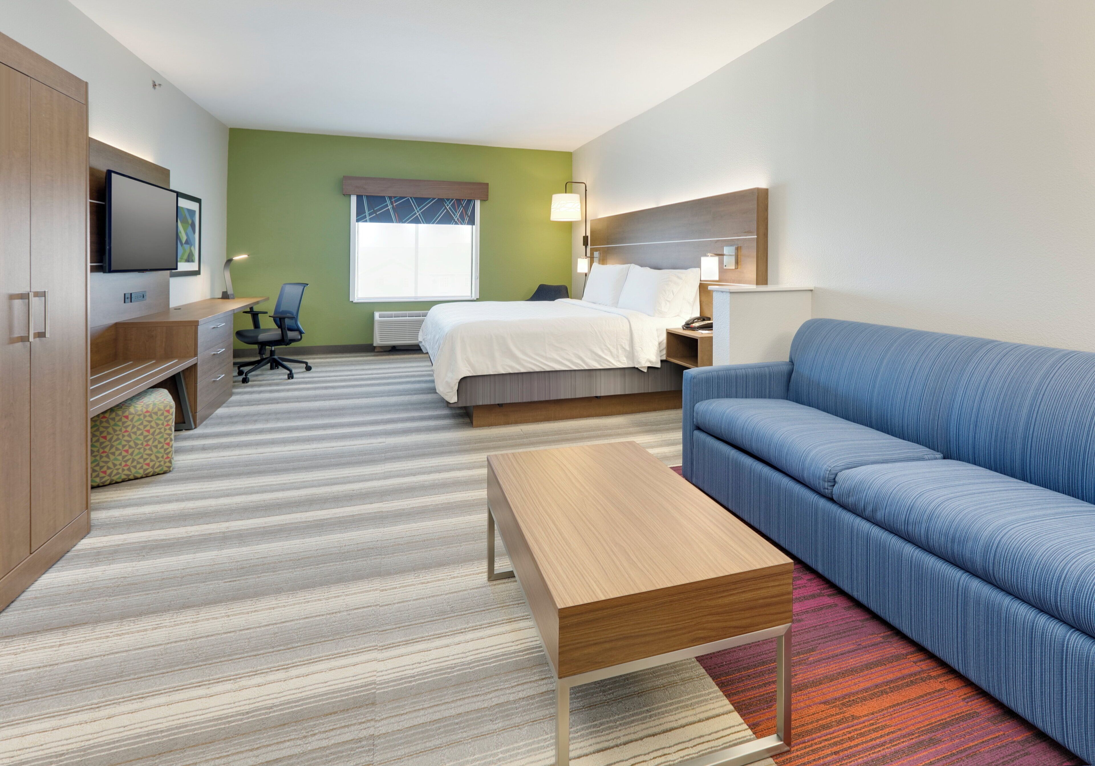 Une chambre d’hôtel avec un lit, un canapé, un bureau et une télévision.